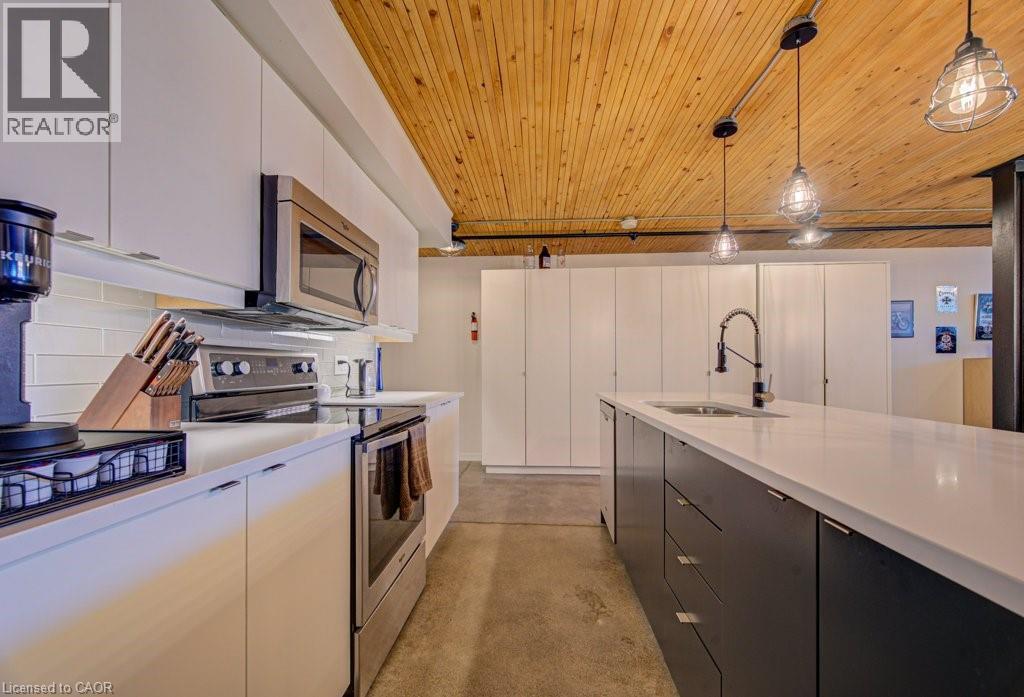 Kitchen with stainless steel appliances, finished concrete floors, two tone cabinets, pendant lighting, and wood ceiling - 85 Spruce Street Unit# 103, Cambridge, ON - Indoor Photo Showing Kitchen