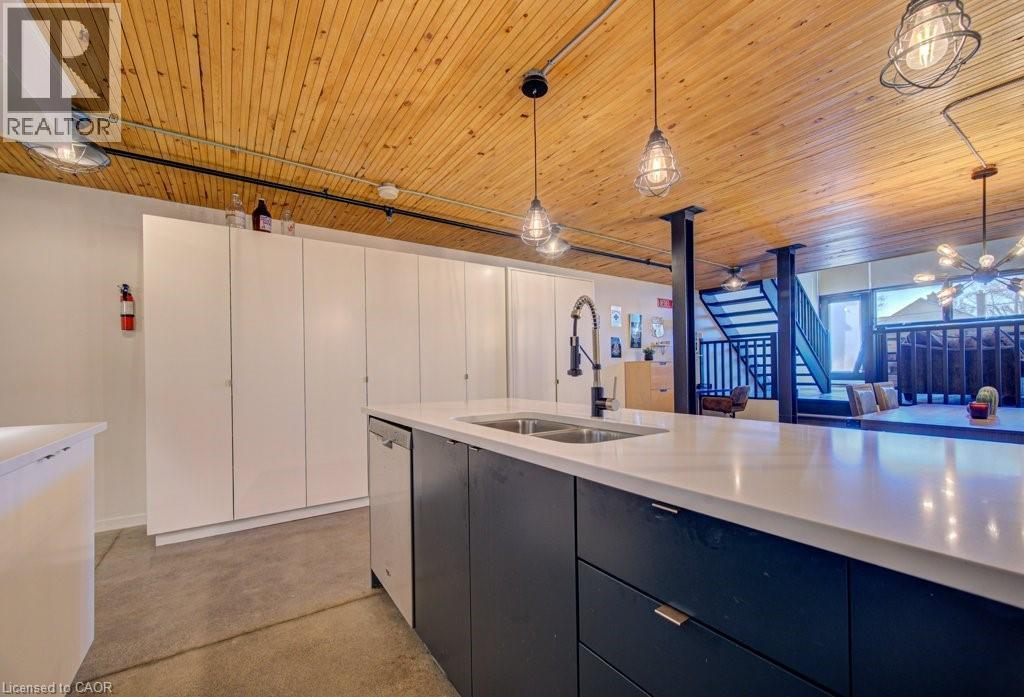 Kitchen with modern cabinets, hanging light fixtures, concrete flooring, wood ceiling, and dishwasher - 85 Spruce Street Unit# 103, Cambridge, ON - Indoor Photo Showing Kitchen With Double Sink