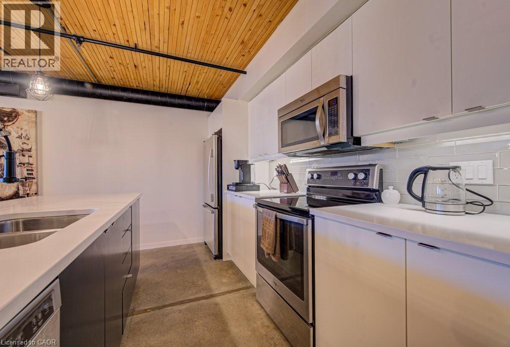 Kitchen featuring stainless steel appliances, wood ceiling, finished concrete floors, hanging light fixtures, and two tone cabinetry - 85 Spruce Street Unit# 103, Cambridge, ON - Indoor Photo Showing Kitchen With Stainless Steel Kitchen With Double Sink