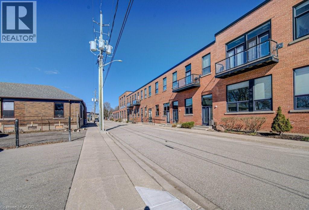 View of asphalt road with street lights, sidewalks, and curbs - 85 Spruce Street Unit# 103, Cambridge, ON - Outdoor