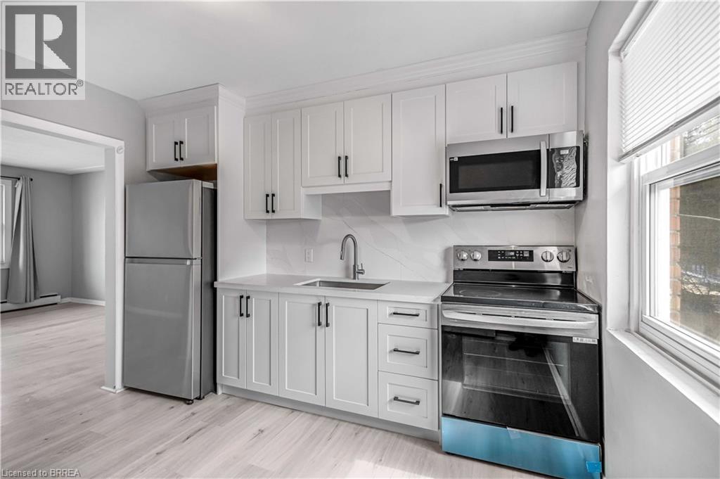 Kitchen featuring stainless steel appliances, white cabinets, light wood-type flooring, baseboard heating, and light stone countertops - 151 Siebert Avenue, Kitchener, ON - Indoor Photo Showing Kitchen