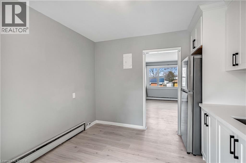 Kitchen featuring a baseboard heating unit, freestanding refrigerator, white cabinetry, light wood-style flooring, and a baseboard radiator - 151 Siebert Avenue, Kitchener, ON - Indoor