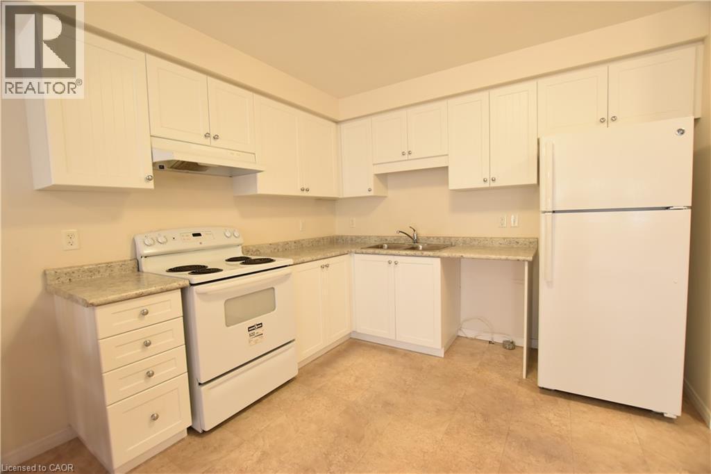 Kitchen with white appliances, white cabinets, and light countertops - 52 Meadowridge Street, Kitchener, ON - Indoor Photo Showing Kitchen With Double Sink