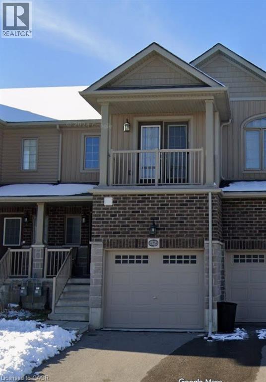 View of front facade featuring board and batten siding, an attached garage, concrete driveway, a balcony, and brick siding - 52 Meadowridge Street, Kitchener, ON - Outdoor With Deck Patio Veranda