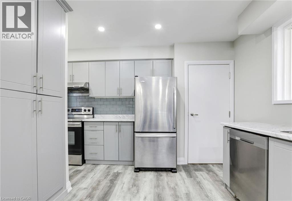 Kitchen with stainless steel appliances, light wood-style floors, tasteful backsplash, recessed lighting, and gray cabinetry - 7 Cardill Crescent, Waterloo, ON - Indoor Photo Showing Kitchen