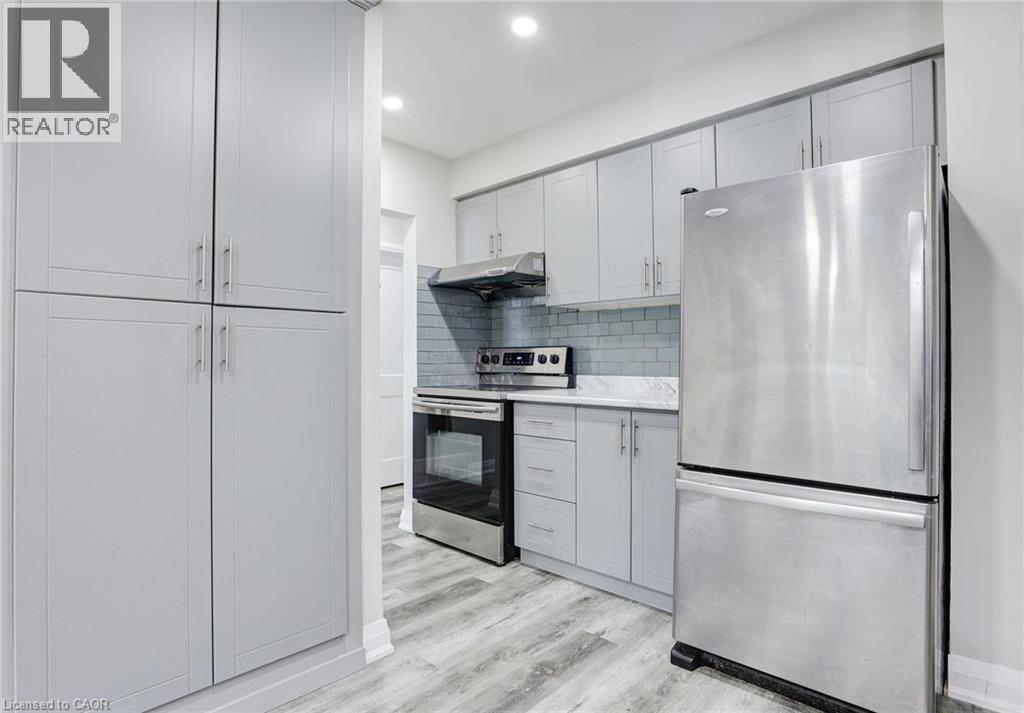 Kitchen with stainless steel appliances, light wood-style floors, backsplash, recessed lighting, and gray cabinetry - 7 Cardill Crescent, Waterloo, ON - Indoor Photo Showing Kitchen