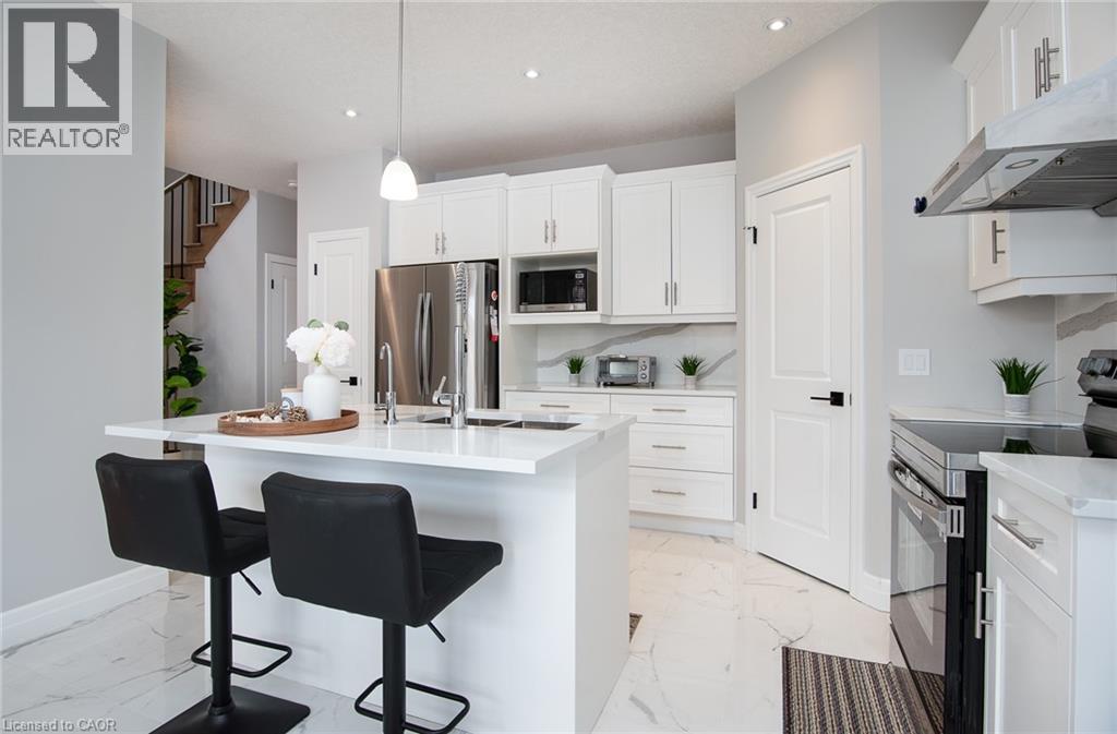Kitchen featuring stainless steel appliances, a breakfast bar area, white cabinetry, and a center island with sink - 346 Chokecherry Crescent, Waterloo, ON - Indoor Photo Showing Kitchen With Upgraded Kitchen