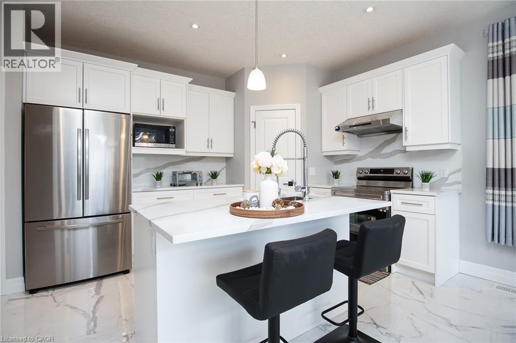 Kitchen featuring stainless steel appliances, white cabinetry, light marble finish flooring, and a breakfast bar area - 346 Chokecherry Crescent, Waterloo, ON - Indoor Photo Showing Kitchen With Upgraded Kitchen