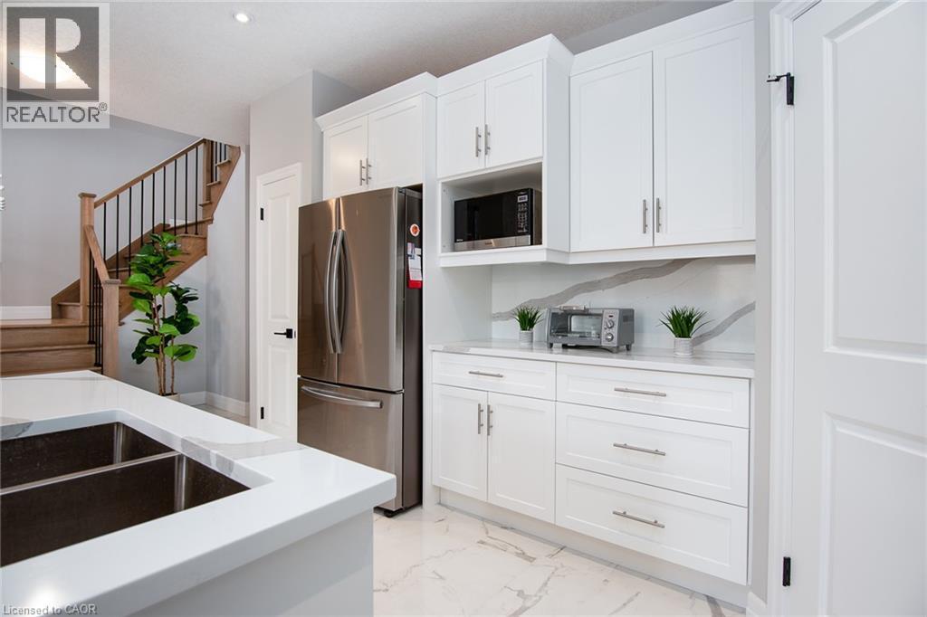 Kitchen featuring stainless steel appliances, white cabinets, light marble finish flooring, and light stone countertops - 346 Chokecherry Crescent, Waterloo, ON - Indoor Photo Showing Kitchen With Double Sink