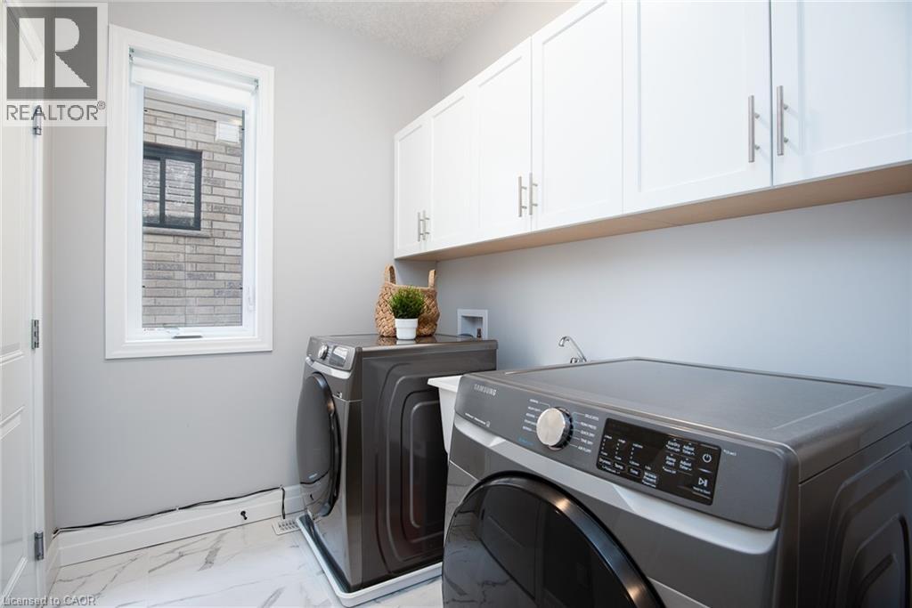 Laundry area with light marble finish flooring, independent washer and dryer, cabinet space, and a textured ceiling - 346 Chokecherry Crescent, Waterloo, ON - Indoor Photo Showing Laundry Room