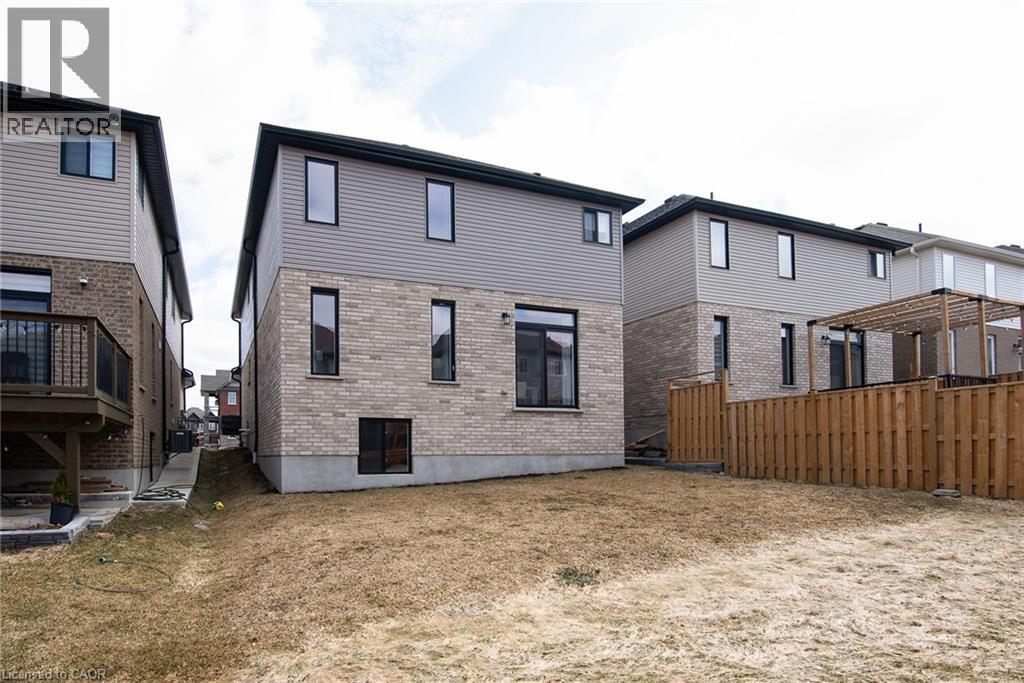 Back of property with brick siding, a lawn, and a wooden deck - 346 Chokecherry Crescent, Waterloo, ON - Outdoor With Exterior