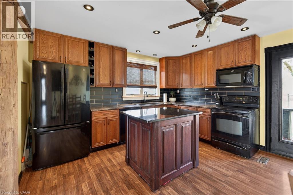 Kitchen with black appliances, dark stone countertops, dark wood finished floors, wood finish cabinets, and a ceiling fan - 703 Dunn Avenue, Hamilton, ON - Indoor Photo Showing Kitchen