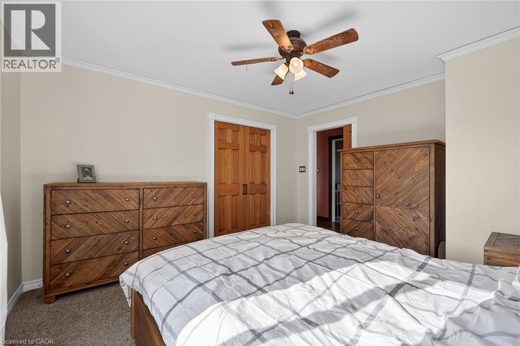 Bedroom with ornamental molding, dark carpet, a ceiling fan, and a closet - 703 Dunn Avenue, Hamilton, ON - Indoor Photo Showing Bedroom