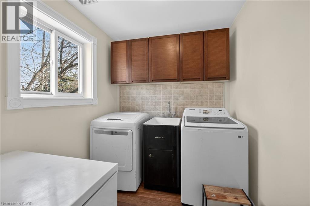 Laundry area featuring washer and dryer, cabinet space, and dark wood-style floors - 703 Dunn Avenue, Hamilton, ON - Indoor Photo Showing Laundry Room