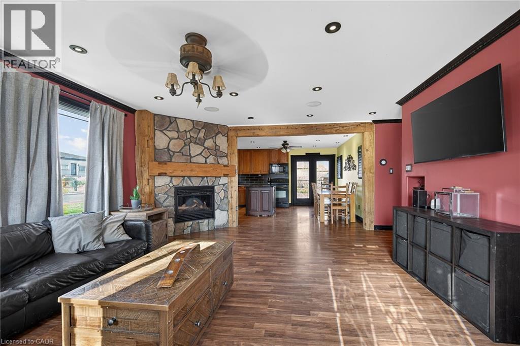 Living area featuring a fireplace, crown molding, dark wood-type flooring, and ceiling fan - 703 Dunn Avenue, Hamilton, ON - Indoor Photo Showing Living Room With Fireplace