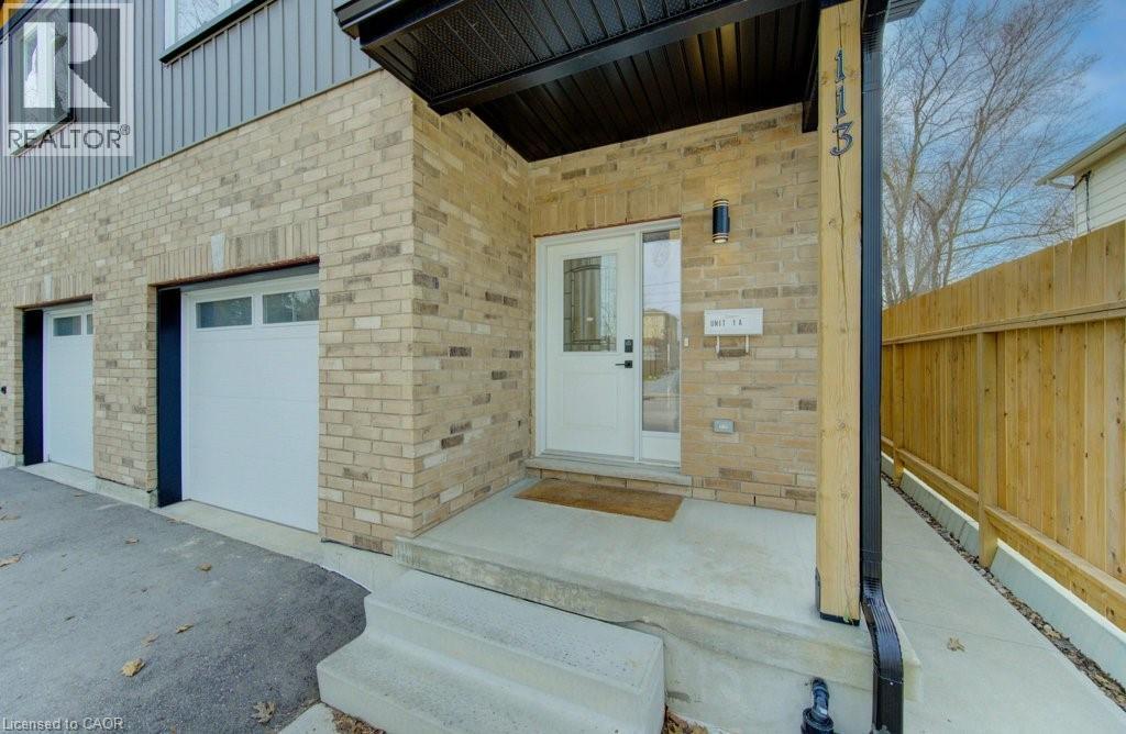 View of exterior entry featuring brick siding, a garage, asphalt driveway, and board and batten siding - 113 Walter Street, Kitchener, ON - Outdoor With Exterior