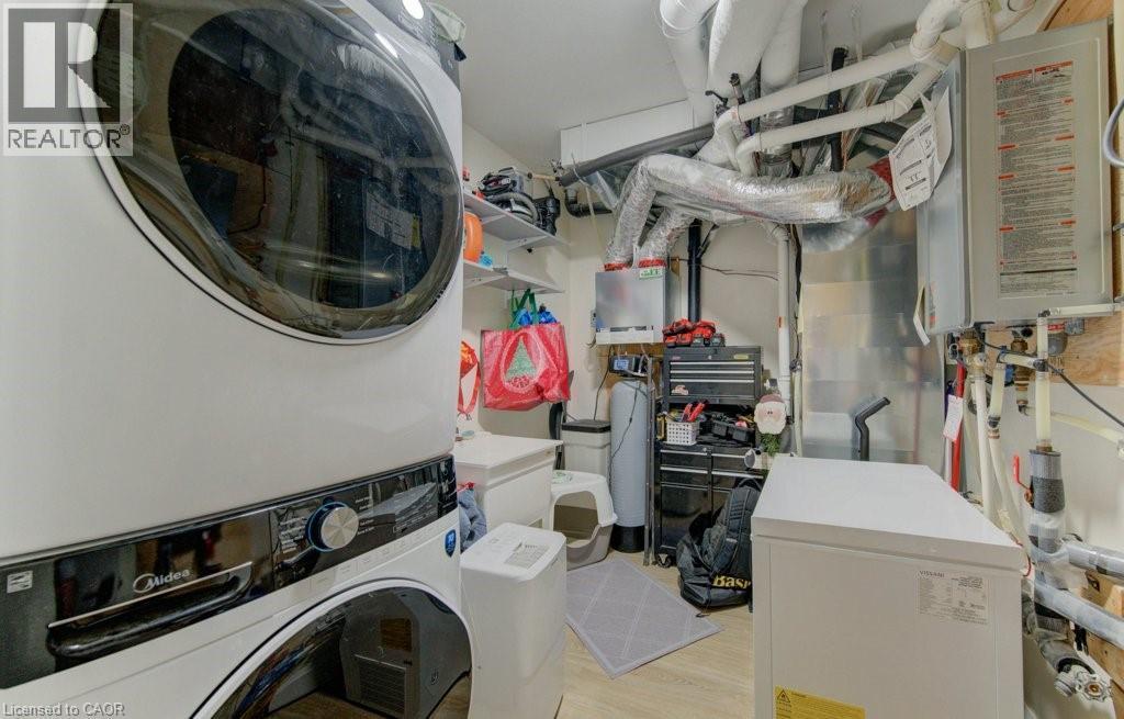 Laundry room with water heater, stacked washing machine and dryer, and light wood-style floors - 113 Walter Street, Kitchener, ON - Indoor Photo Showing Laundry Room