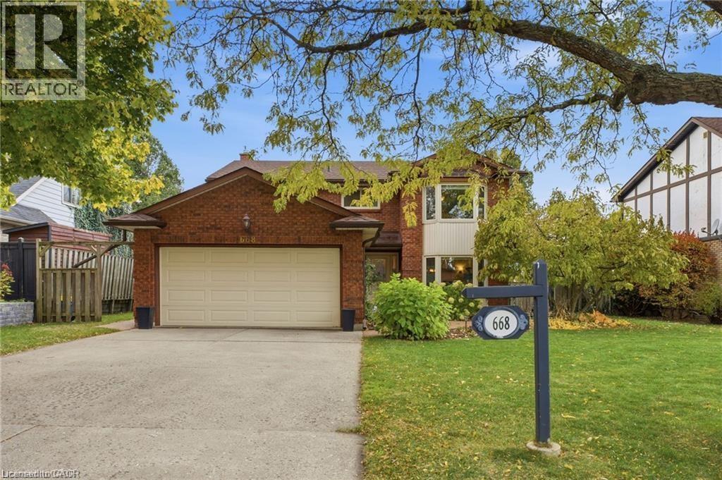 Traditional-style home featuring an attached garage, brick siding, and driveway - 668 Tomahawk Crescent, Ancaster, ON - Outdoor