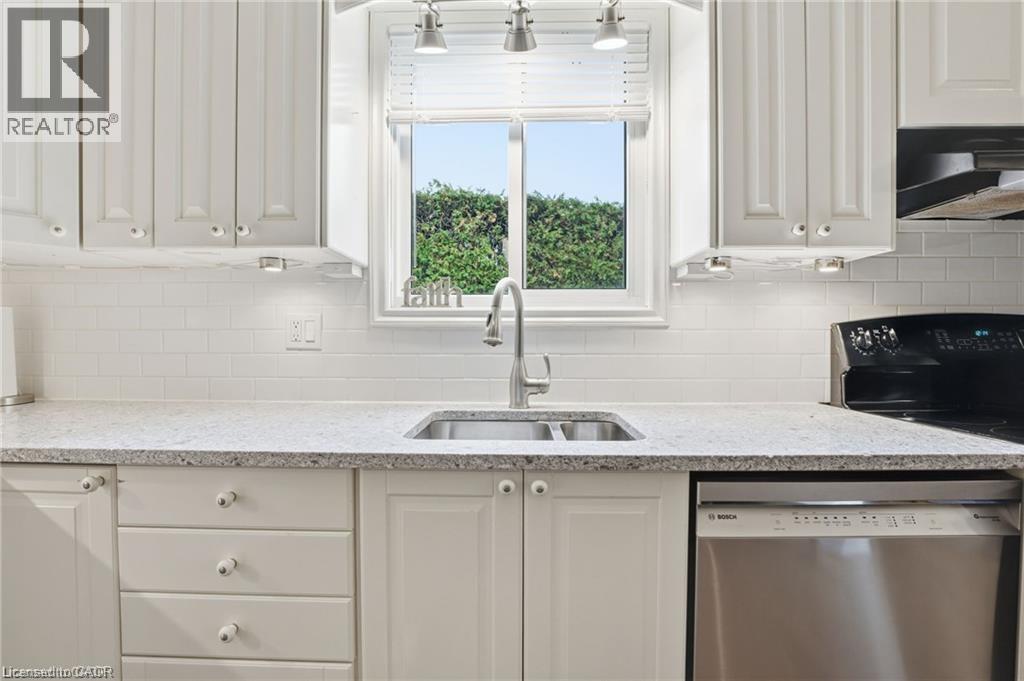 Kitchen with dishwasher, light stone countertops, white cabinetry, and range hood - 668 Tomahawk Crescent, Ancaster, ON - Indoor Photo Showing Kitchen With Double Sink