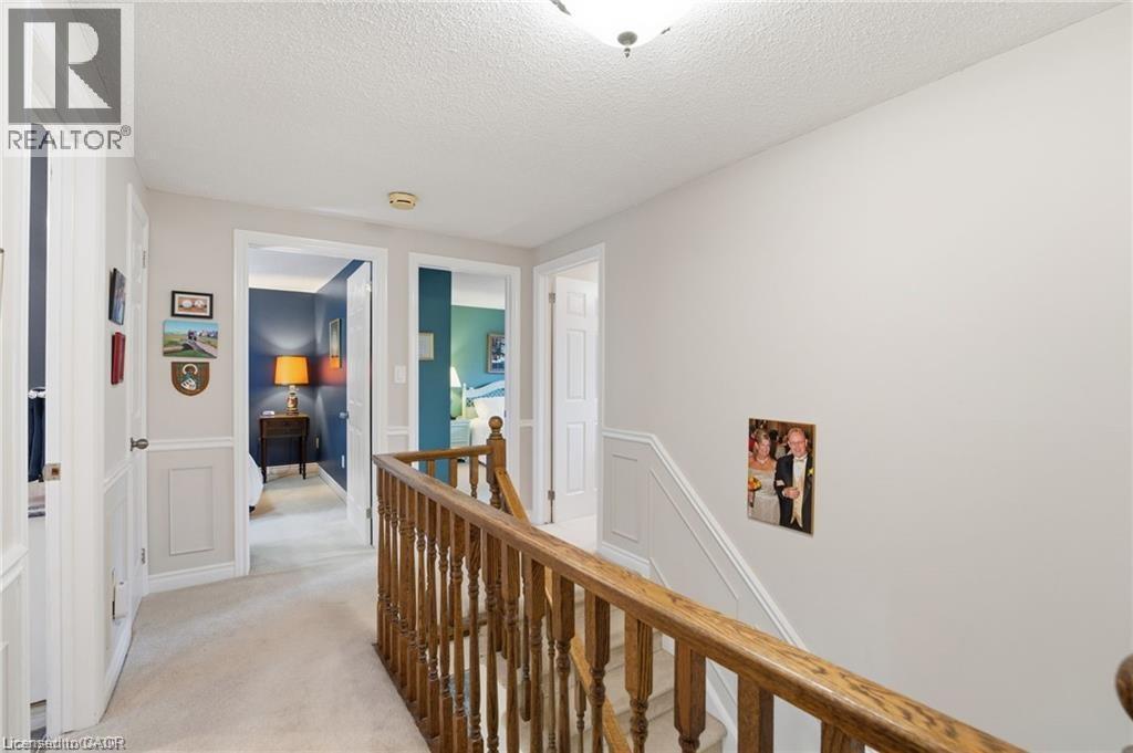Hallway with an upstairs landing, light carpet, a textured ceiling, a decorative wall, and wainscoting - 668 Tomahawk Crescent, Ancaster, ON - Indoor Photo Showing Other Room