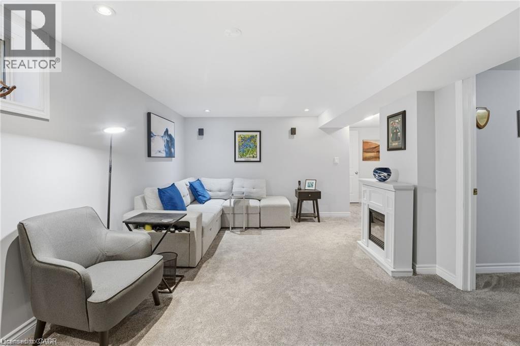 Living room with a glass covered fireplace, light colored carpet, and recessed lighting - 668 Tomahawk Crescent, Ancaster, ON - Indoor