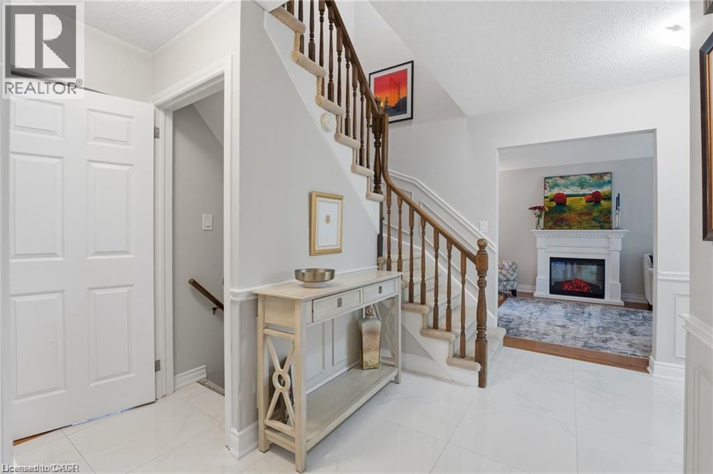 Stairway with a glass covered fireplace, a textured ceiling, and tile patterned floors - 668 Tomahawk Crescent, Ancaster, ON - Indoor Photo Showing Other Room