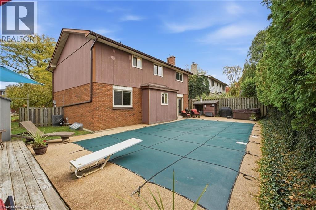Rear view of property featuring a patio, a fenced backyard, brick siding, and a chimney - 668 Tomahawk Crescent, Ancaster, ON - Outdoor With Deck Patio Veranda With Exterior