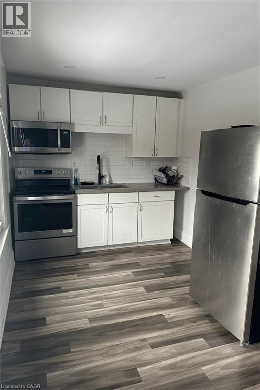 Kitchen featuring white cabinets, dark hardwood / wood-style floors, sink, and appliances with stainless steel finishes - 1090 Cannon Street E, Hamilton, ON - Indoor Photo Showing Kitchen