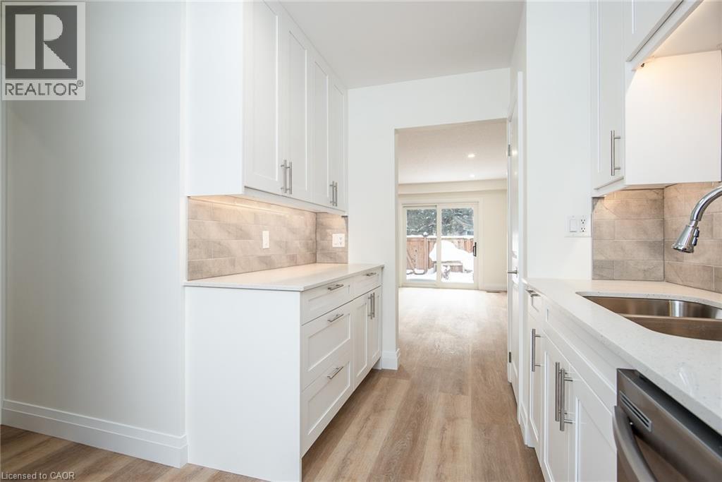Kitchen featuring light stone countertops, white cabinets, and stainless steel dishwasher - 27 Queenston Drive, Kitchener, ON - Indoor Photo Showing Kitchen With Double Sink