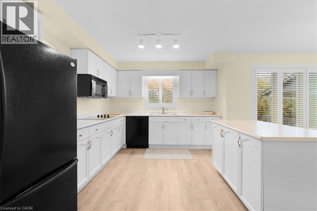 Kitchen featuring black appliances, white cabinets, light wood finished floors, light countertops, and a center island - 90 Westlawn Drive, Hamilton, ON - Indoor Photo Showing Kitchen