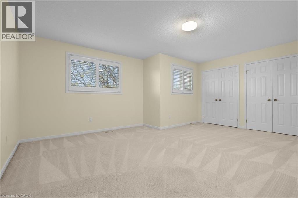 Unfurnished bedroom with light colored carpet, two closets, and a textured ceiling - 90 Westlawn Drive, Hamilton, ON - Indoor Photo Showing Other Room