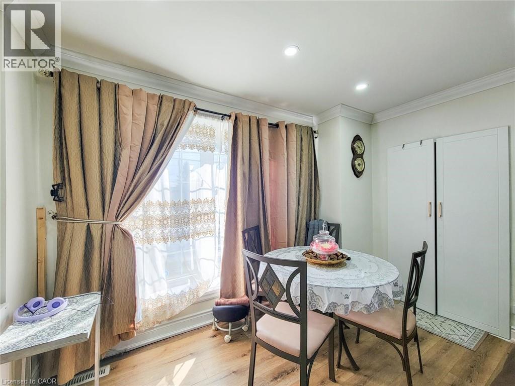 Dining area featuring wood-finish flooring, recessed lighting, crown molding, and a large window with privacy sheers and drapes - 823 Queensdale Avenue E, Hamilton, ON - Indoor Photo Showing Dining Room
