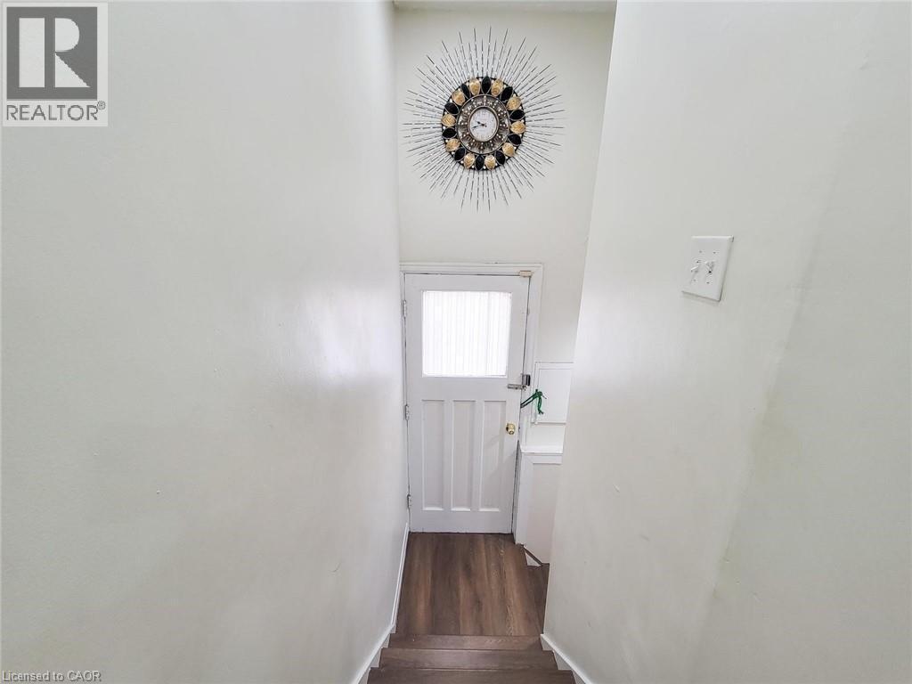 White paneled door with frosted glass window and wood-finish flooring - 823 Queensdale Avenue E, Hamilton, ON - Indoor Photo Showing Other Room