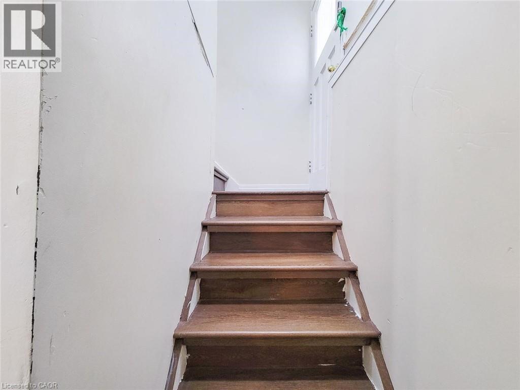 Wood-finish staircase with white risers and light-colored walls - 823 Queensdale Avenue E, Hamilton, ON - Indoor Photo Showing Other Room