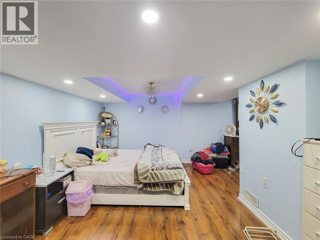 Spacious room featuring wood-finish flooring, light blue walls, and white baseboards - 823 Queensdale Avenue E, Hamilton, ON - Indoor Photo Showing Bedroom
