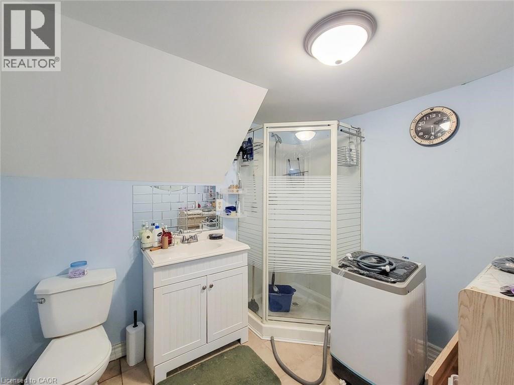 Bathroom featuring a corner shower enclosure with frosted glass, a white vanity with cabinet storage, and a white toilet - 823 Queensdale Avenue E, Hamilton, ON - Indoor Photo Showing Bathroom