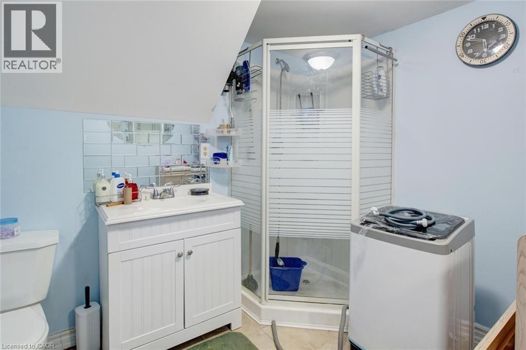 Corner shower enclosure with frosted glass panels, white beadboard vanity with integrated sink, and light blue wall finish - 823 Queensdale Avenue E, Hamilton, ON - Indoor Photo Showing Bathroom