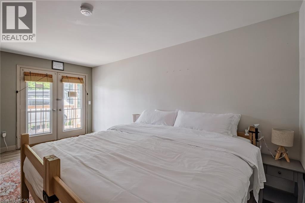 Bedroom featuring french doors, access to exterior, and wood finished floors - 30 John Street, Port Dover, ON