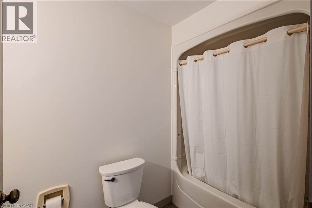 Bathroom featuring toilet and shower / bath combination with curtain - 30 John Street, Port Dover, ON