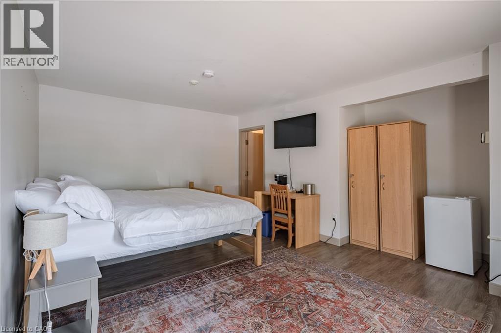 Bedroom featuring dark wood-style floors and white refrigerator - 30 John Street, Port Dover, ON