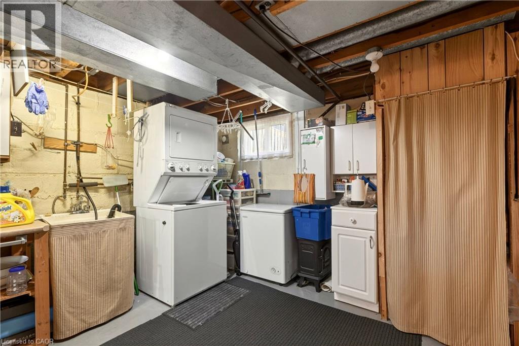 Laundry room featuring cabinet space, concrete flooring, and stacked washer / dryer - 944 Garth Street, Hamilton, ON - Indoor Photo Showing Laundry Room