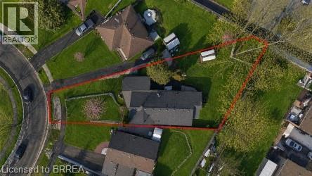 Large parcel featuring a single-story residence with a dark-shingle roof, extensive green lawn areas, mature trees, and a paved driveway leading to a circular road - 71 Pinecrest Drive, Kitchener, ON - Outdoor With View