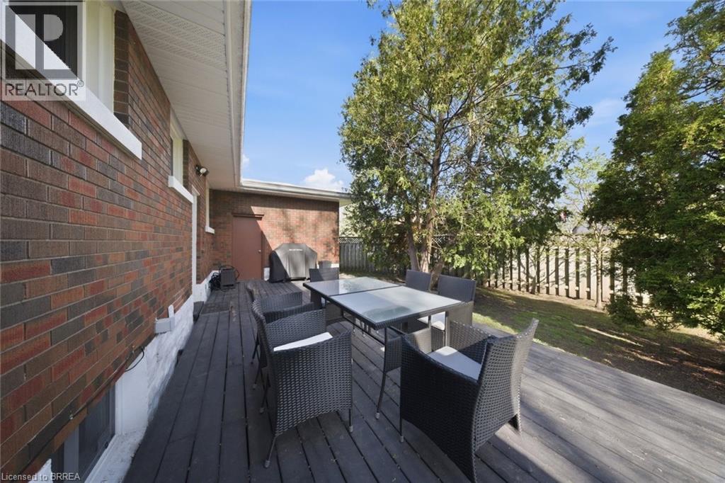 Expansive wood-finish deck bordered by a brick exterior and a privacy fence - 71 Pinecrest Drive, Kitchener, ON - Outdoor With Deck Patio Veranda With Exterior