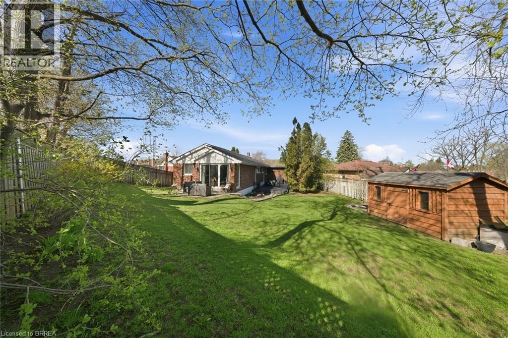 Expansive sloped backyard featuring a manicured lawn, mature trees, and a detached wooden shed - 71 Pinecrest Drive, Kitchener, ON - Outdoor