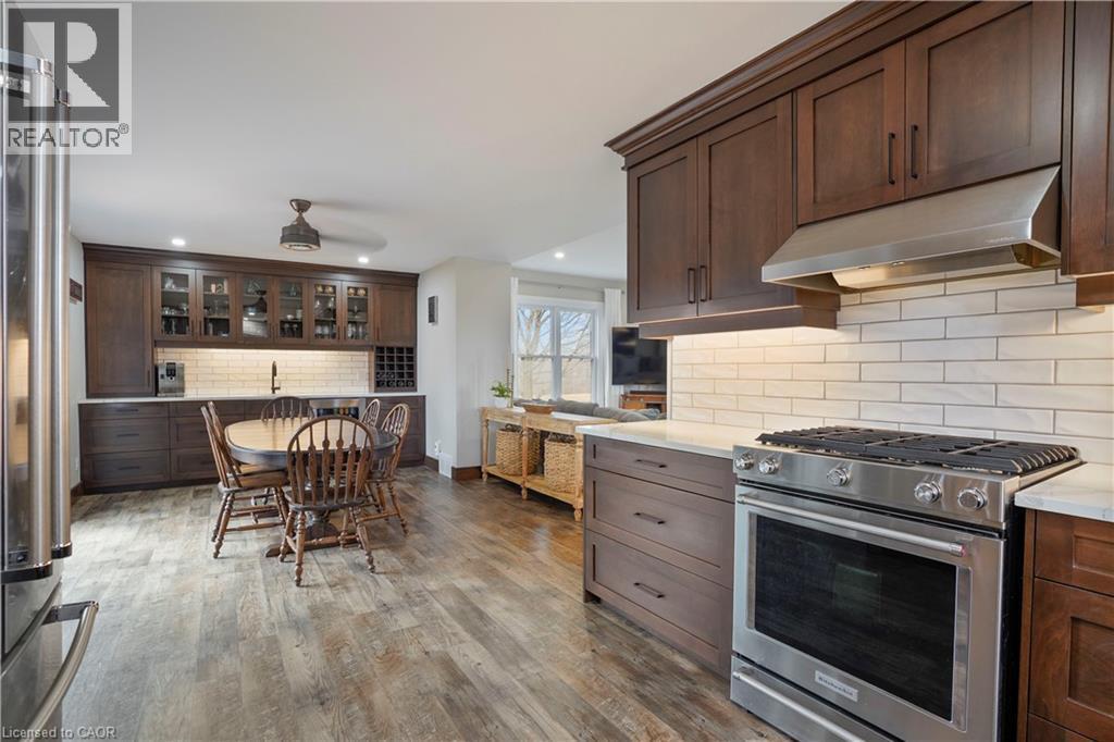 Kitchen with stainless steel appliances, dark wood finish cabinets, glass insert cabinets, dark wood-style floors, and decorative backsplash - 23247 Beattie Line, Elgin, ON - Indoor Photo Showing Kitchen