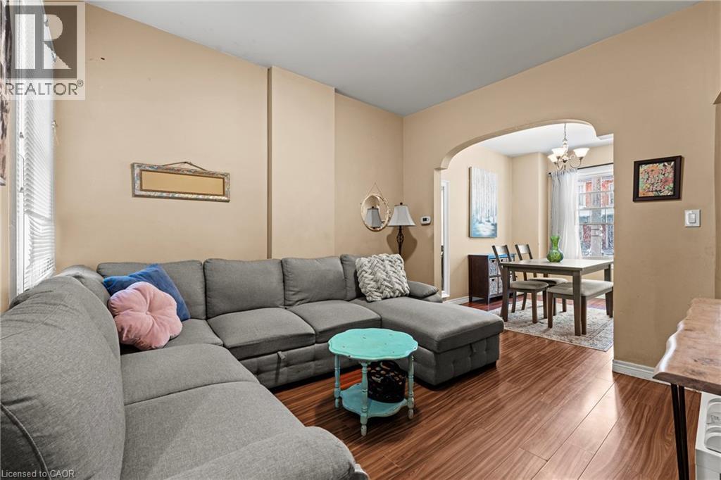 Living area with arched walkways, wood finished floors, and a chandelier - 78 Clyde Street, Hamilton, ON - Indoor Photo Showing Living Room
