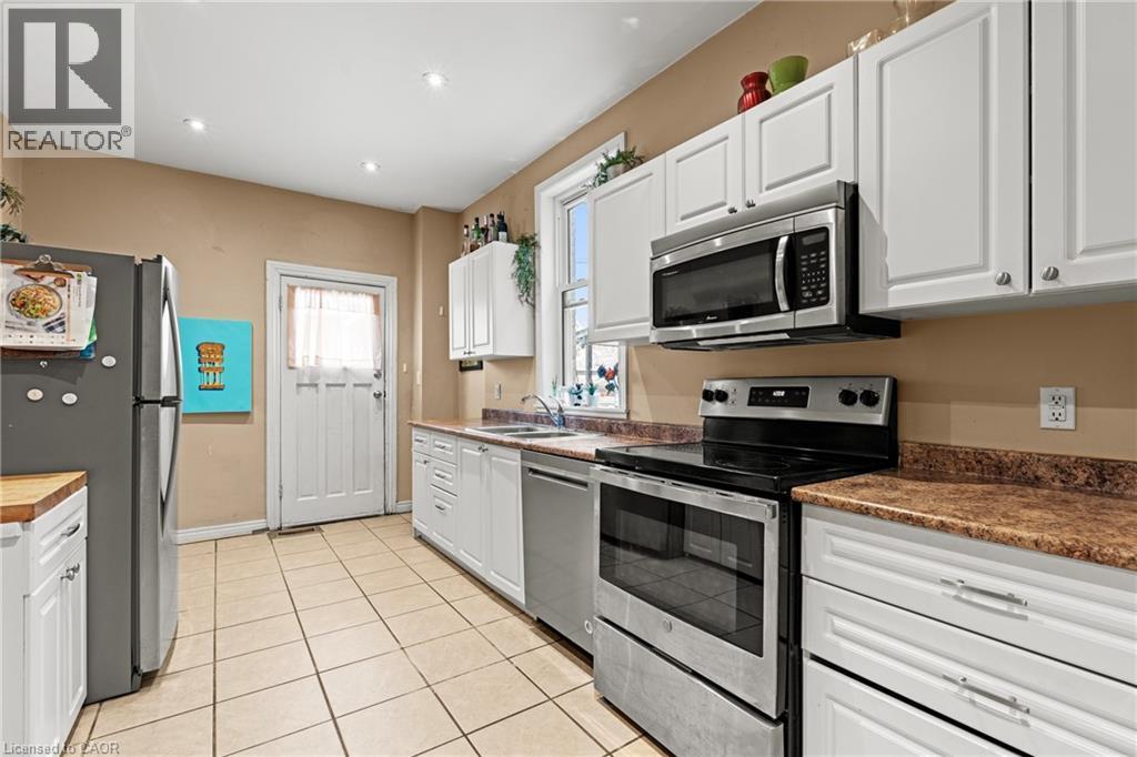 Kitchen with stainless steel appliances, white cabinetry, light tile patterned floors, dark countertops, and recessed lighting - 78 Clyde Street, Hamilton, ON - Indoor Photo Showing Kitchen