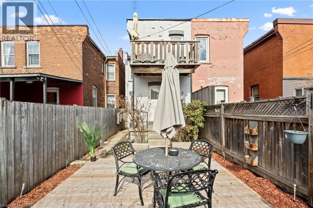 Private outdoor space featuring a wood-finish deck with surrounding fencing, an upper-level balcony, and a ground-level exterior door - 78 Clyde Street, Hamilton, ON - Outdoor With Deck Patio Veranda With Exterior