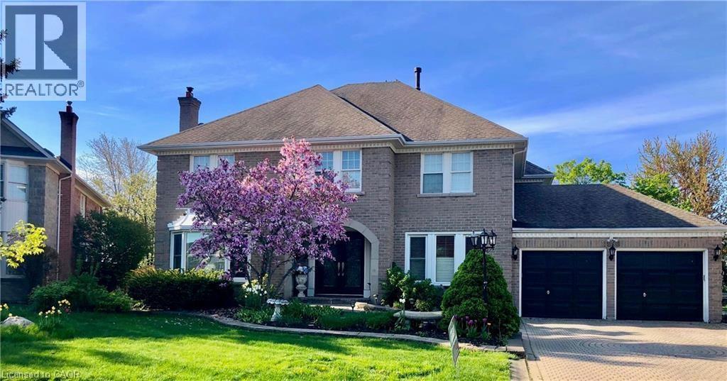 View of front of property featuring a garage, decorative driveway, a front lawn, and a chimney - 2056 Hadfield Court, Burlington, ON - Outdoor