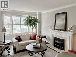 Living area featuring wood finished floors, crown molding, a textured ceiling, and a glass covered fireplace -